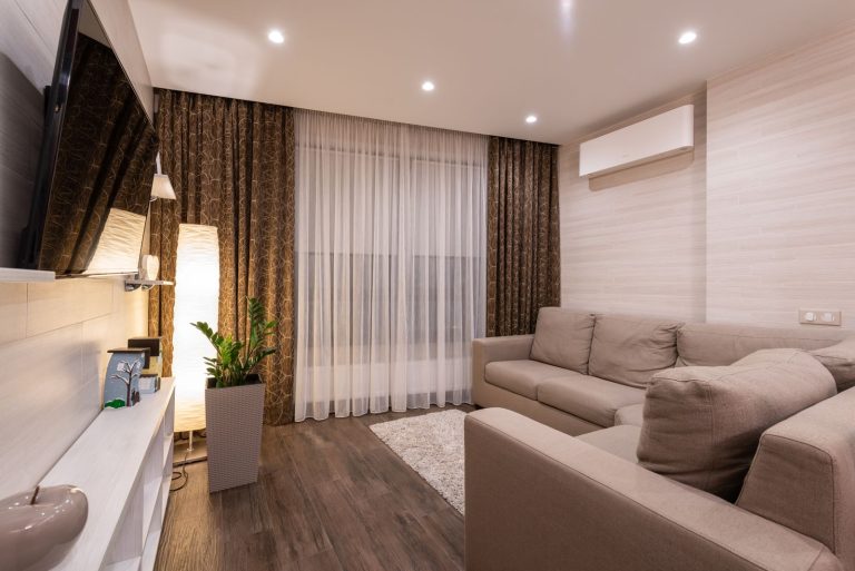 Gemütliches Wohnzimmer mit Ecksofa und Klimagerät über dem Sofa