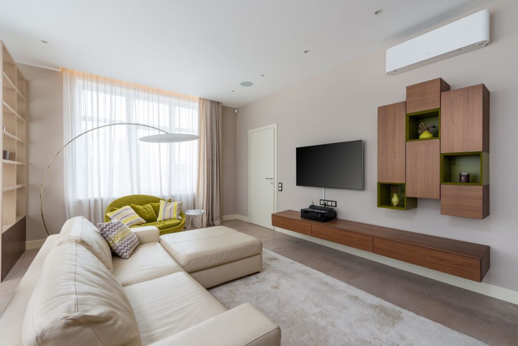 Helles Wohnzimmer mit Sofa und Klimagerät an der Wand